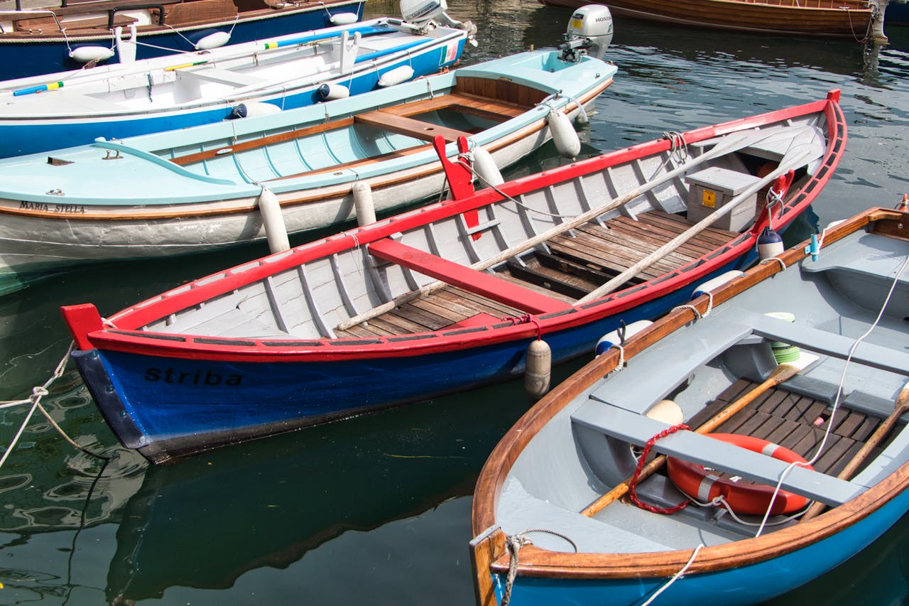 Vibrant wooden boats docked in Malcesine, Veneto, Italy, on a sunny day.